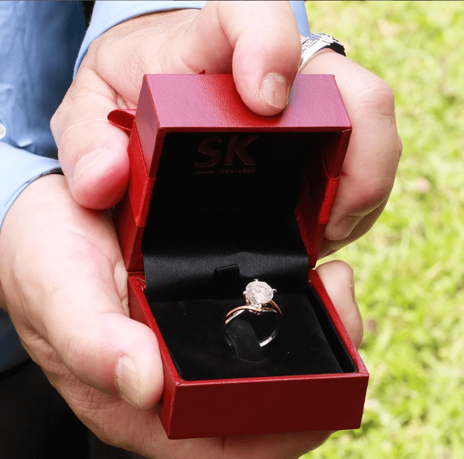 a person presenting solitaire engagement ring when proposing