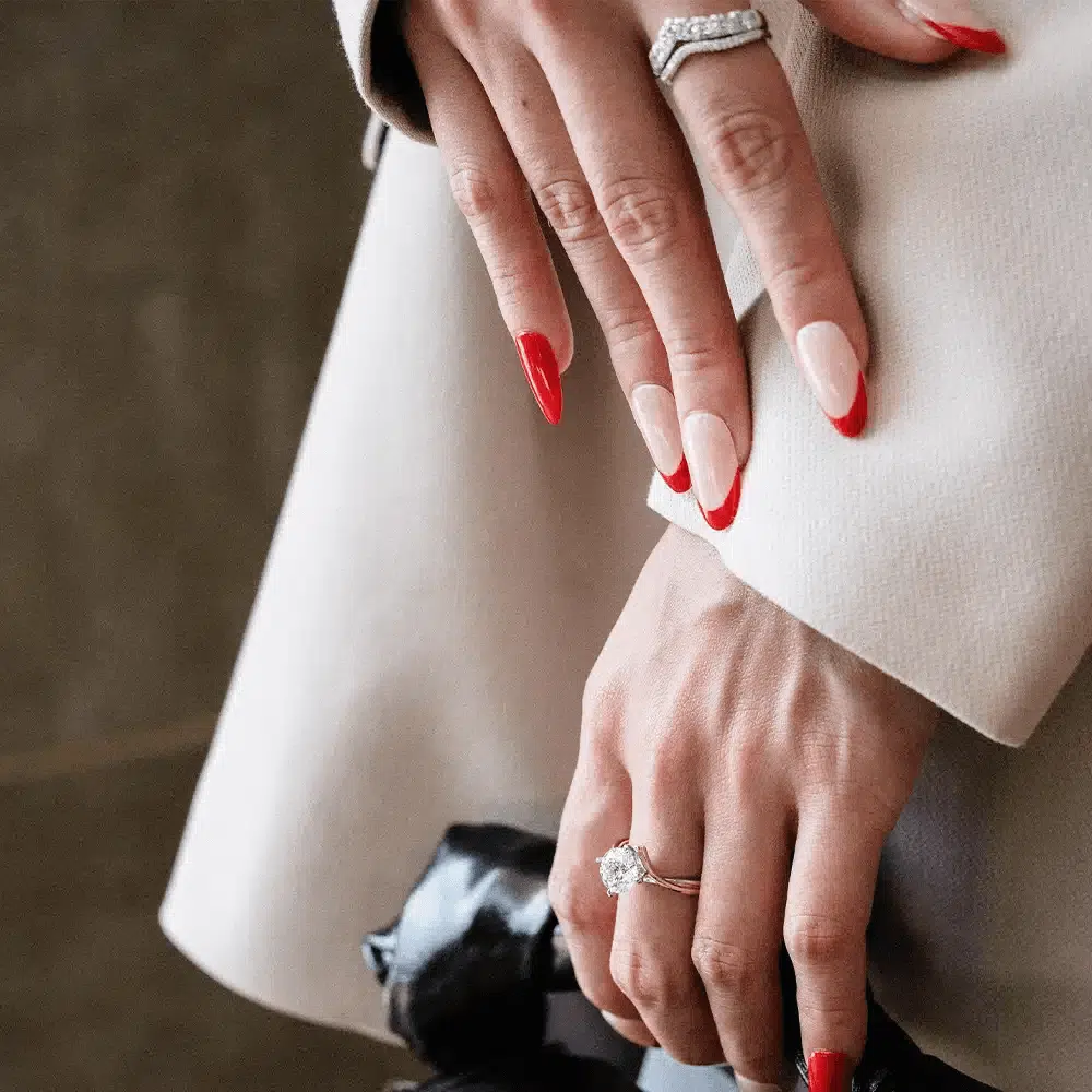 SK a close up of a woman wearing rose gold diamond ring with an alluring and timeless design with four prongs in white gold and rose gold and lab grown diamond on her middle finger